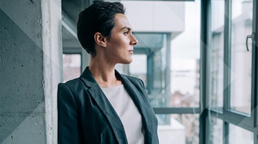 Shot of beautiful businesswoman standing in her office and looking through window.