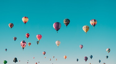 Hot air balloons dot the sky.
