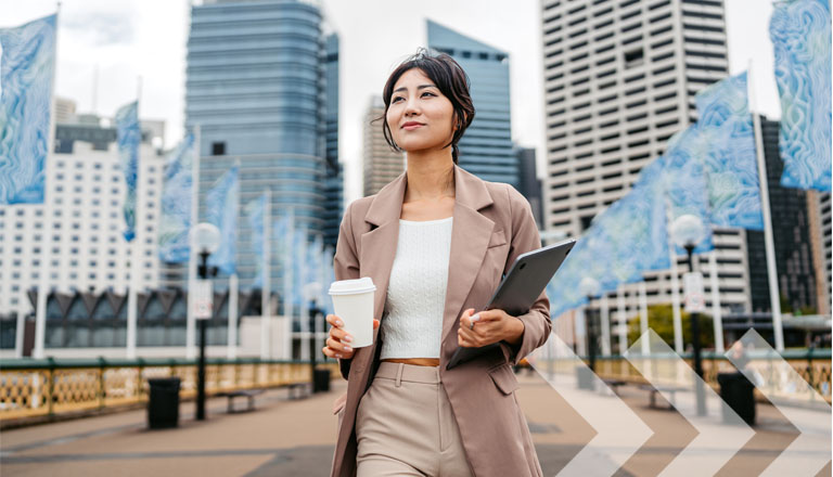 Jeune femme d'affaires asiatique buvant un café à emporter tout en tenant un ordinateur portable à Darling Harbor, à Sydney, en Australie.