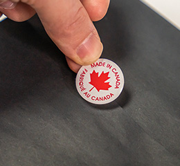 A closeup of a small business owner’s hands applying a Made in Canada sticker to merchandise. 